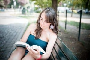 Image of a woman on a bench reading a book.