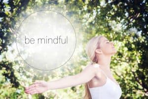 image of a blond woman stretching and the glowing ords "be mindful" floating behind her head