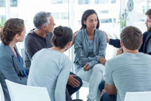 A woman is comforted by others in therapy group