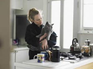 woman holding her cat in the kitchen with coffee