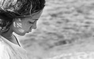 sad young woman staring at beach